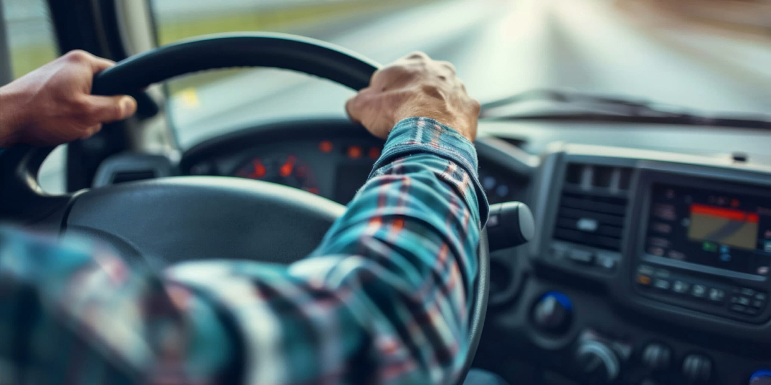 Trucker driving a truck with both hands on steering wheel
