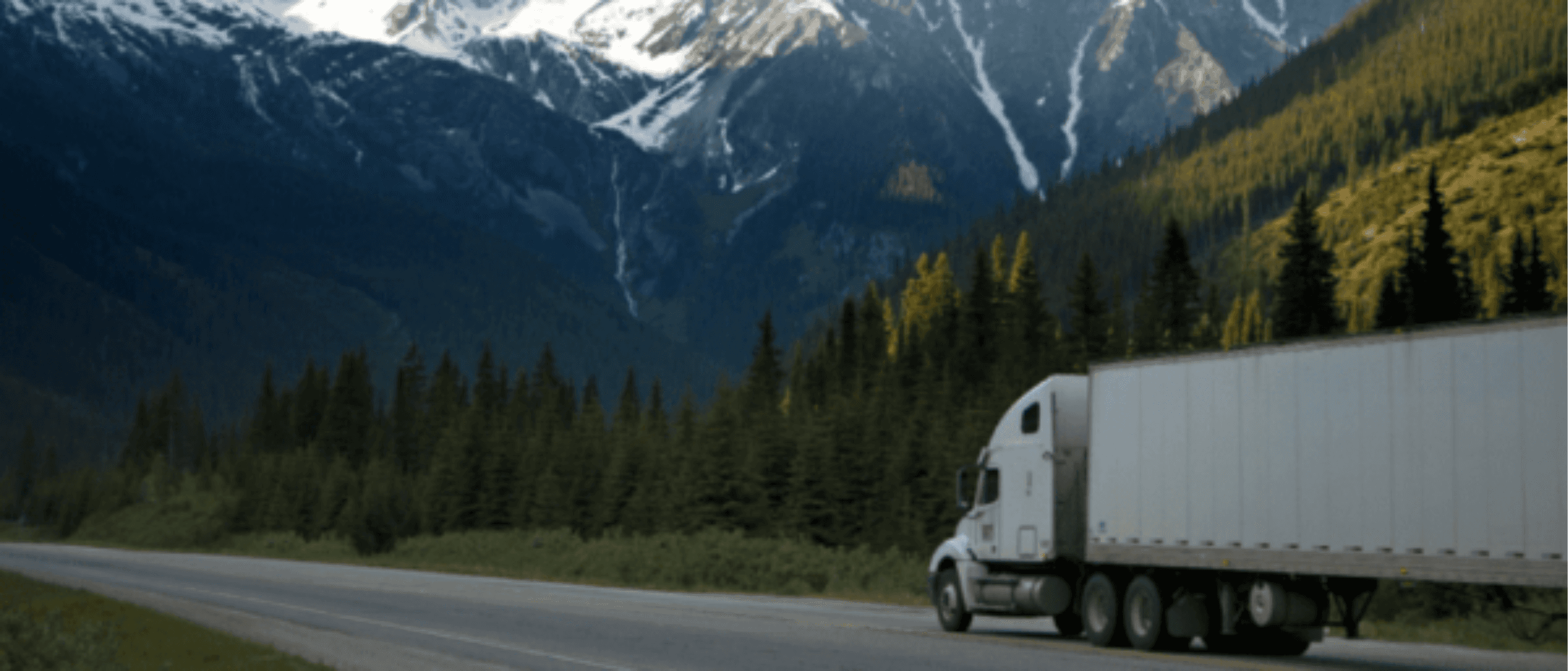 Truck driving down highway with a beautiful view of the mountains